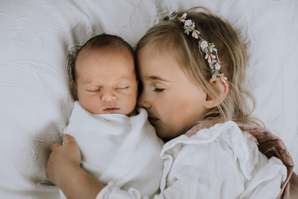 big sister holding little baby sleeping