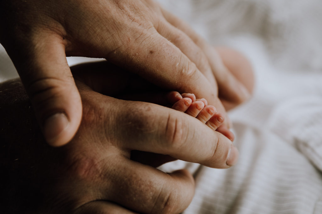 tiny abby toes in dads fingers on white background