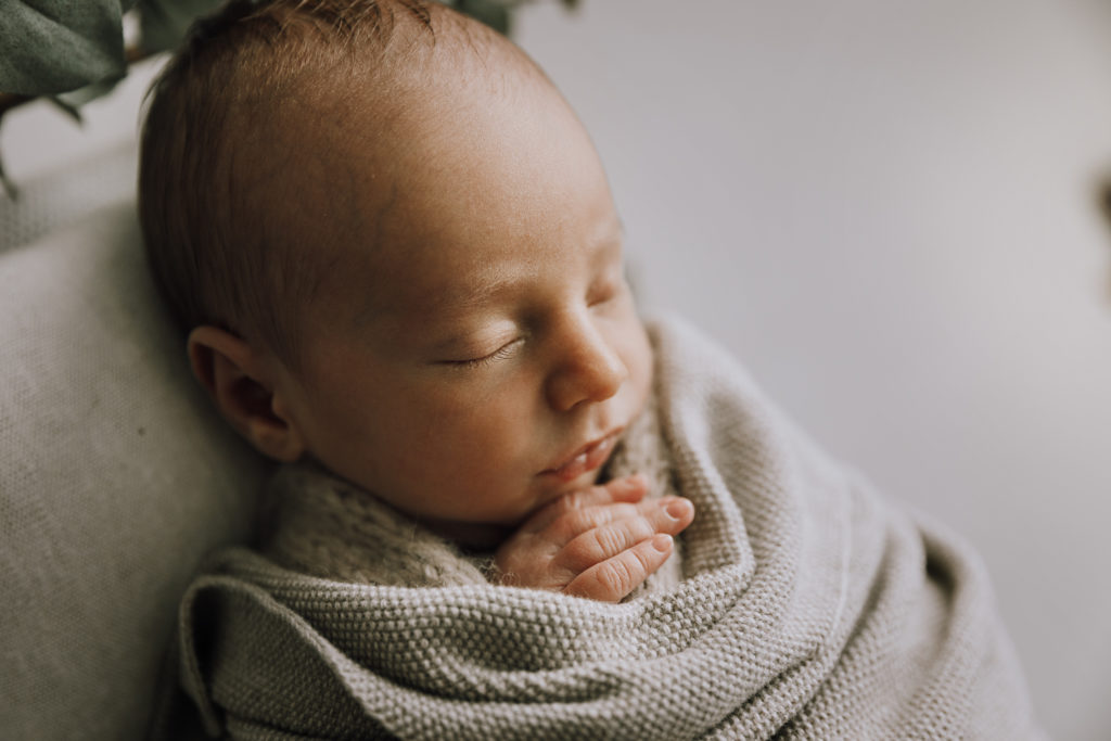 close up of baby boy in a textured neutral wrap