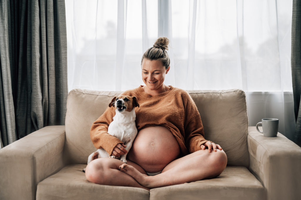 EXPECTING MUM ON COUCH WITH FUNNY DOG