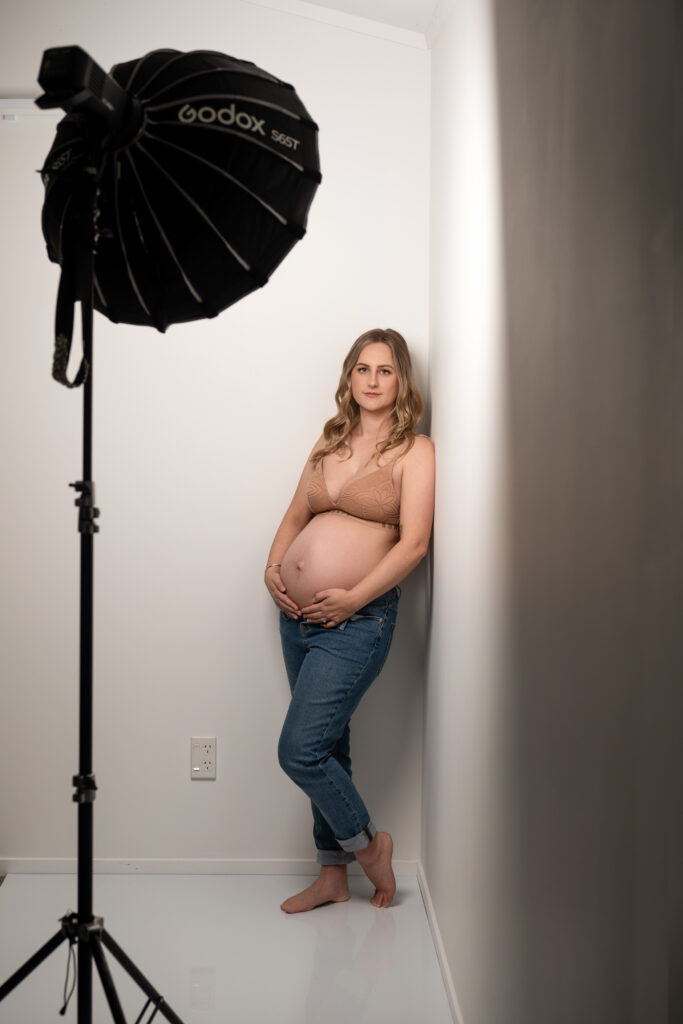behind the scenes , maternity shoot mumma in bra and jeans leaning against the wall