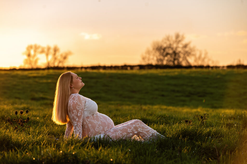 sun setting behind sitting mum, maternity bump showing