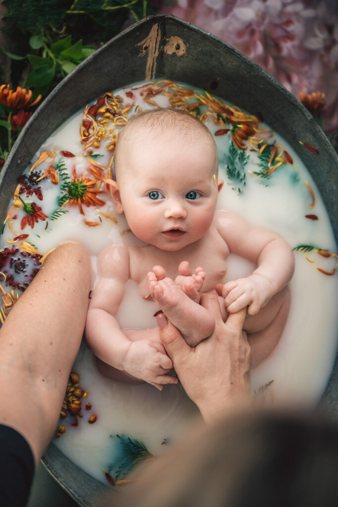 baby girl in milk bath with orange flowers 

